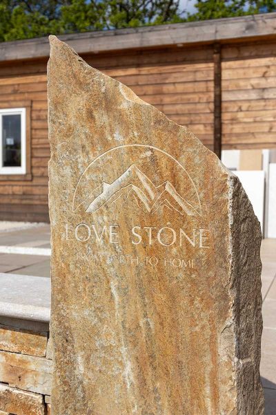 Bespoke stone sign showing the Love Stone Logo in front of the display area at their yard in Ewshot