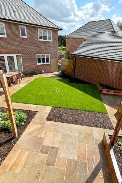 Newly landscaped garden featuring Rippon Buff sandstone paving, edging stones, and timber sleepers from Love Stone in Ewshot Surrey